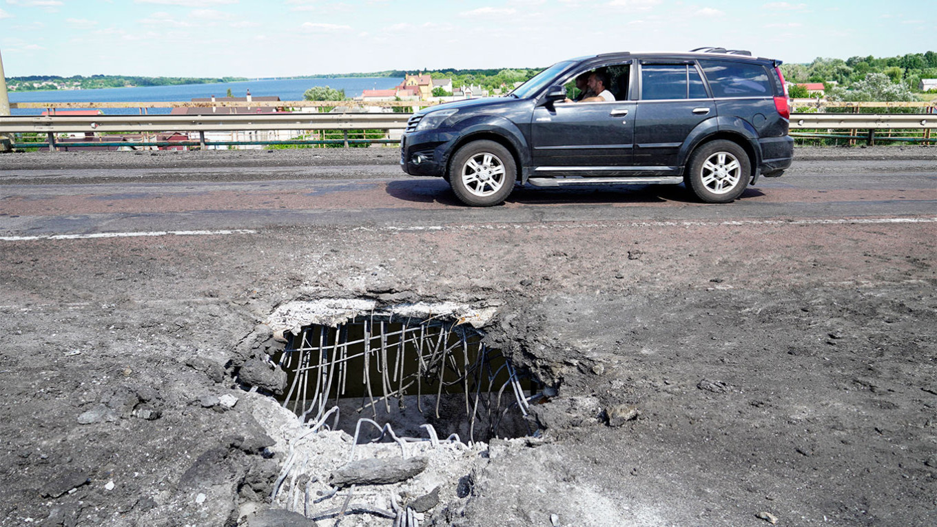 
					A car moving past a crater on Kherson's Antonovskiy Bridge across the Dnipro river.					 					STRINGER / AFP				
