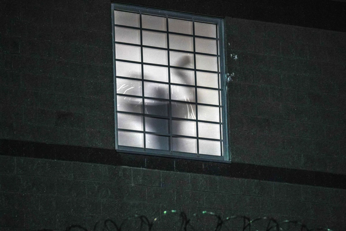 
					The silhouette of a person is seen through the window of an ICE detention center.					 					Ryan Murphy / AFP				