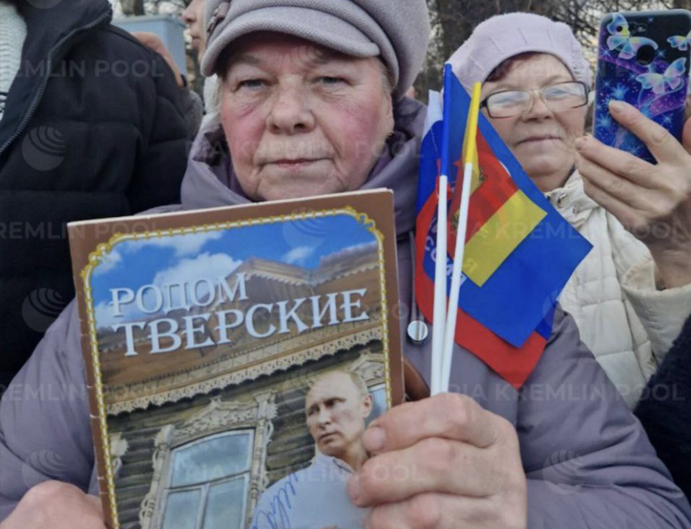 
					A woman in Torzhok holds up her book that Putin had just signed.					 					RIA_Kremlinpool / Telegram				