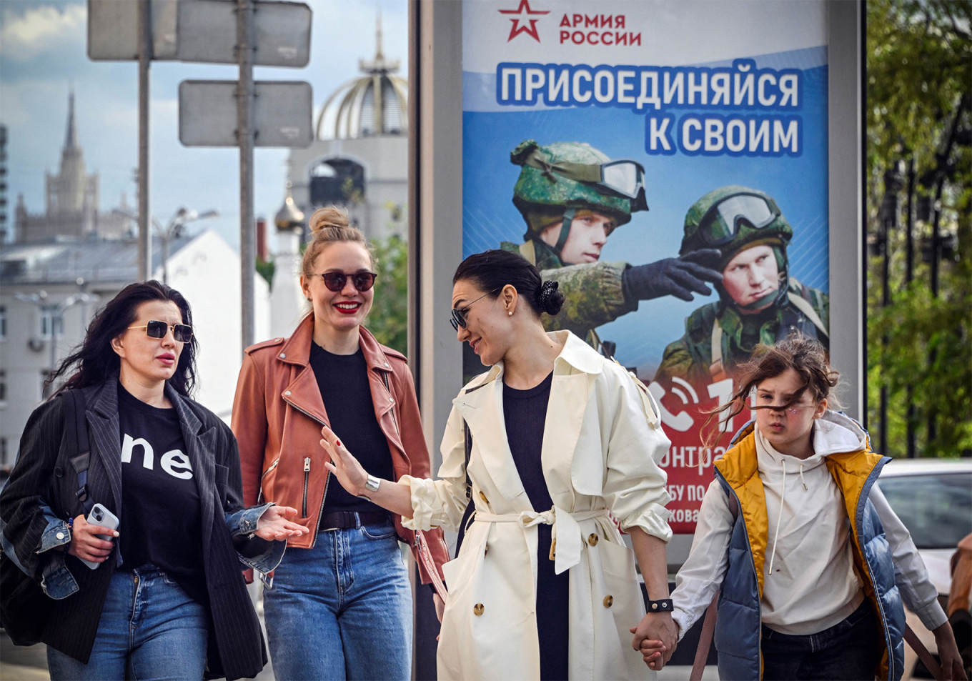 
					Women walk in front of an army recruitment poster in Moscow.					 					Alexander Nemenov / AFP				