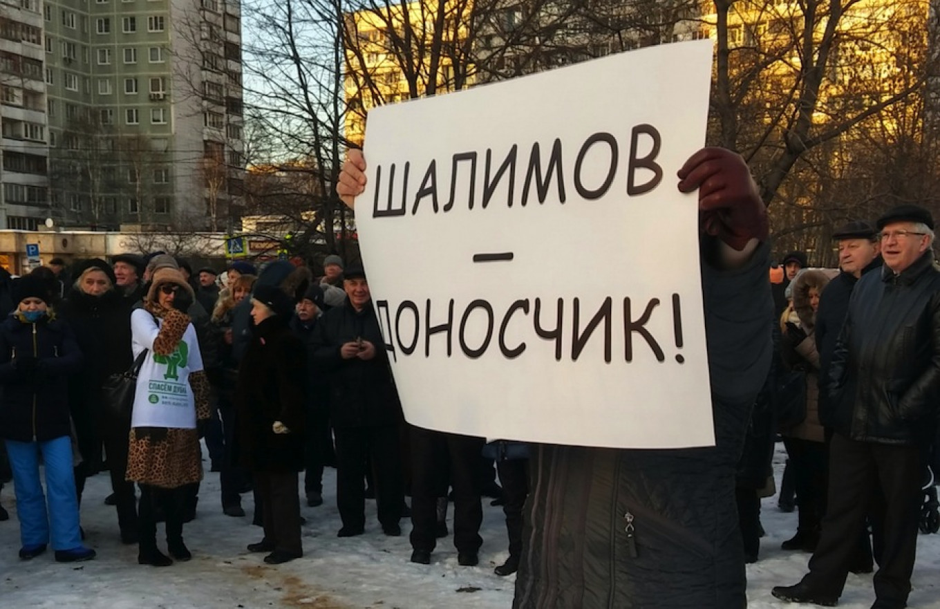 
					Protesters gather in the park in northern Moscow and one protester holds a placard describing local priest Oleg Shalimov as a ‘snitch.’					 					Eva Hartog / MT				