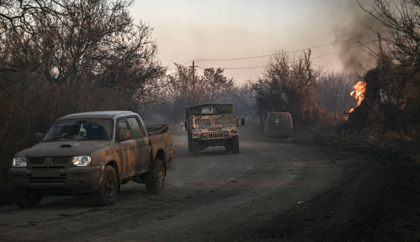 
					Ukrainian military vehicles drive past burning land after white phosphorus munitions exploded in the air at the village of Chasiv Yar near Bakhmut.					 					Aris Messinis / AFP				