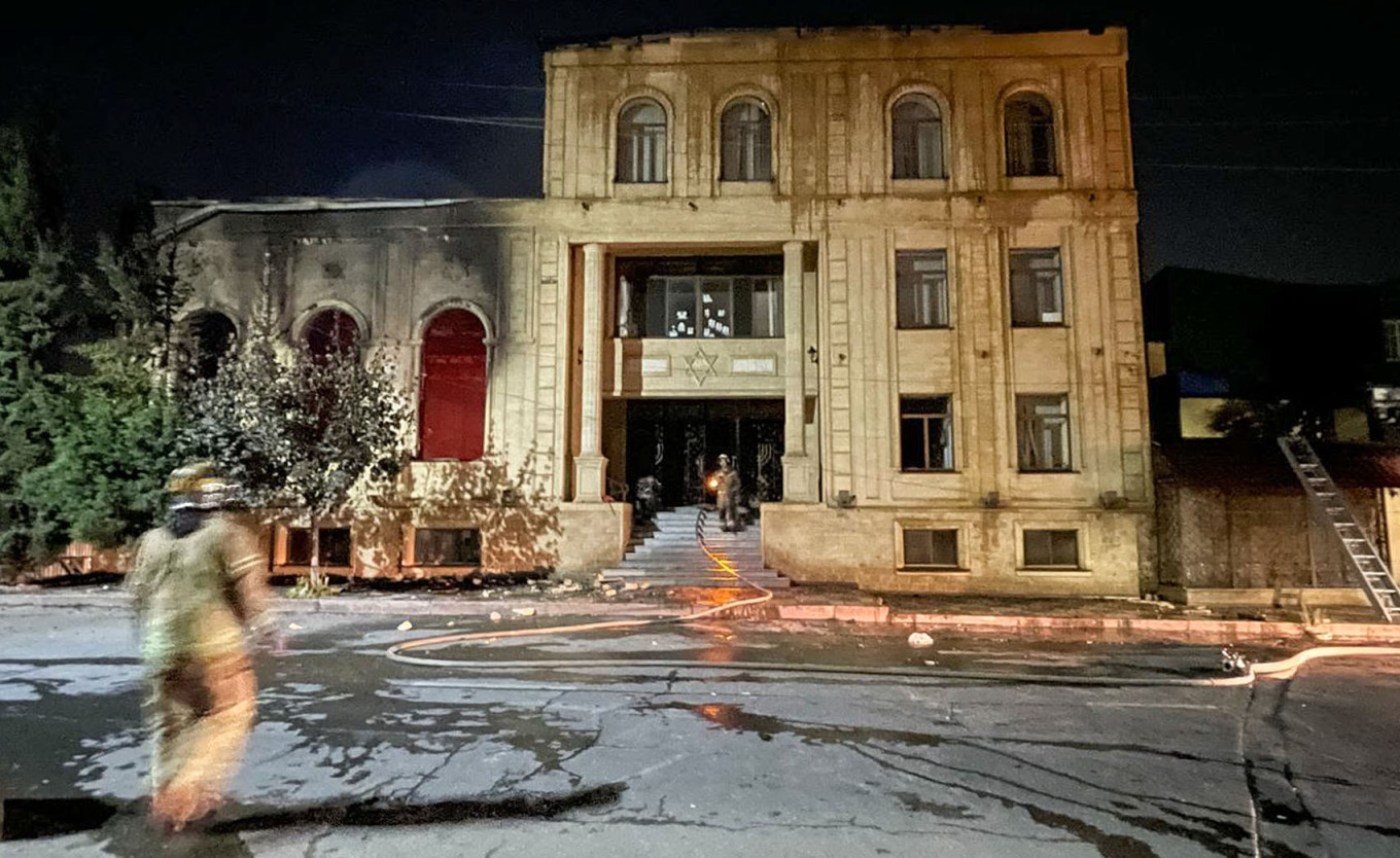 
					Emergency workers approach a burned-out synagogue in Derbent.					 					Gyanzhevi Gadzhibalayev / TASS				