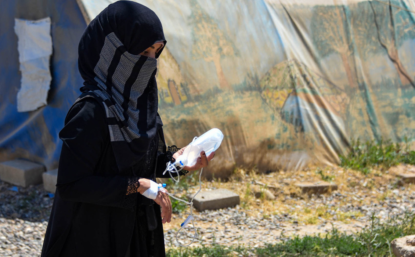 
					A woman walks with a saline infusion on her hand at the Al-Amal Camp.					 					Zaid AL-Obeidi / AFP				