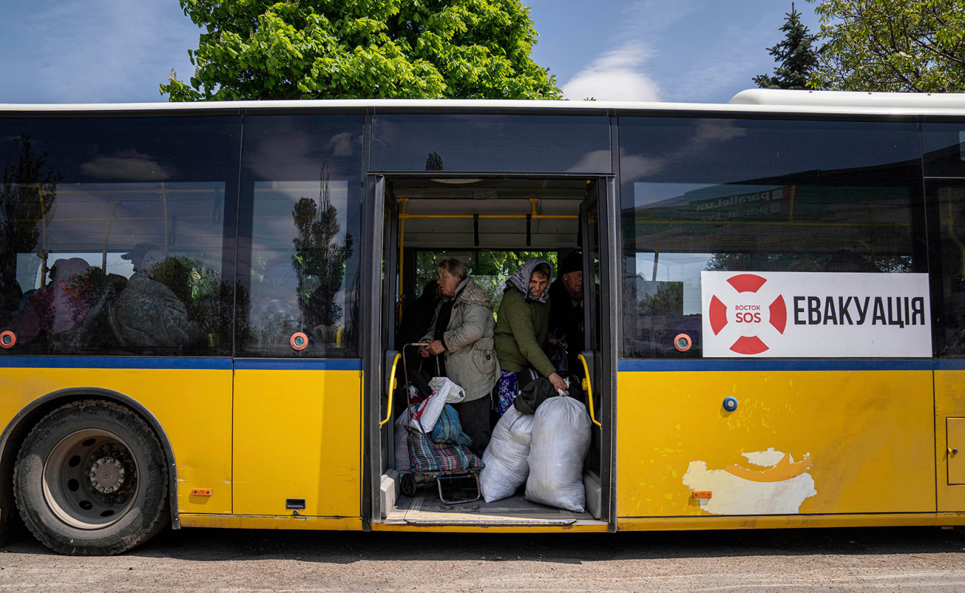 People stand in a bus during an evacuation near Lyman, Ukraine. Evgeniy Maloletka / AP Photo / TASS