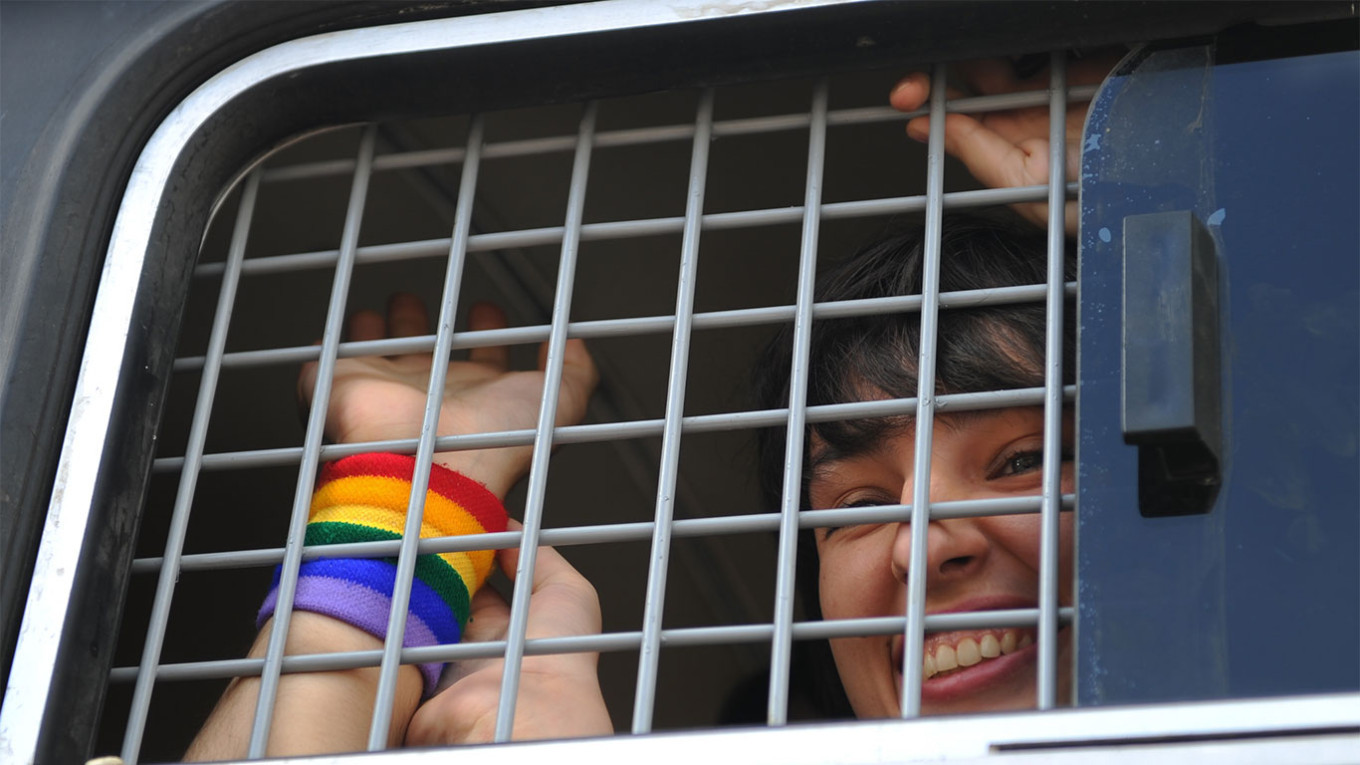 
					A demonstrator looks out of a police vehicle after being detained during an unauthorized rally staged by gay activists.					 					Mitya Aleshkovsky / TASS				