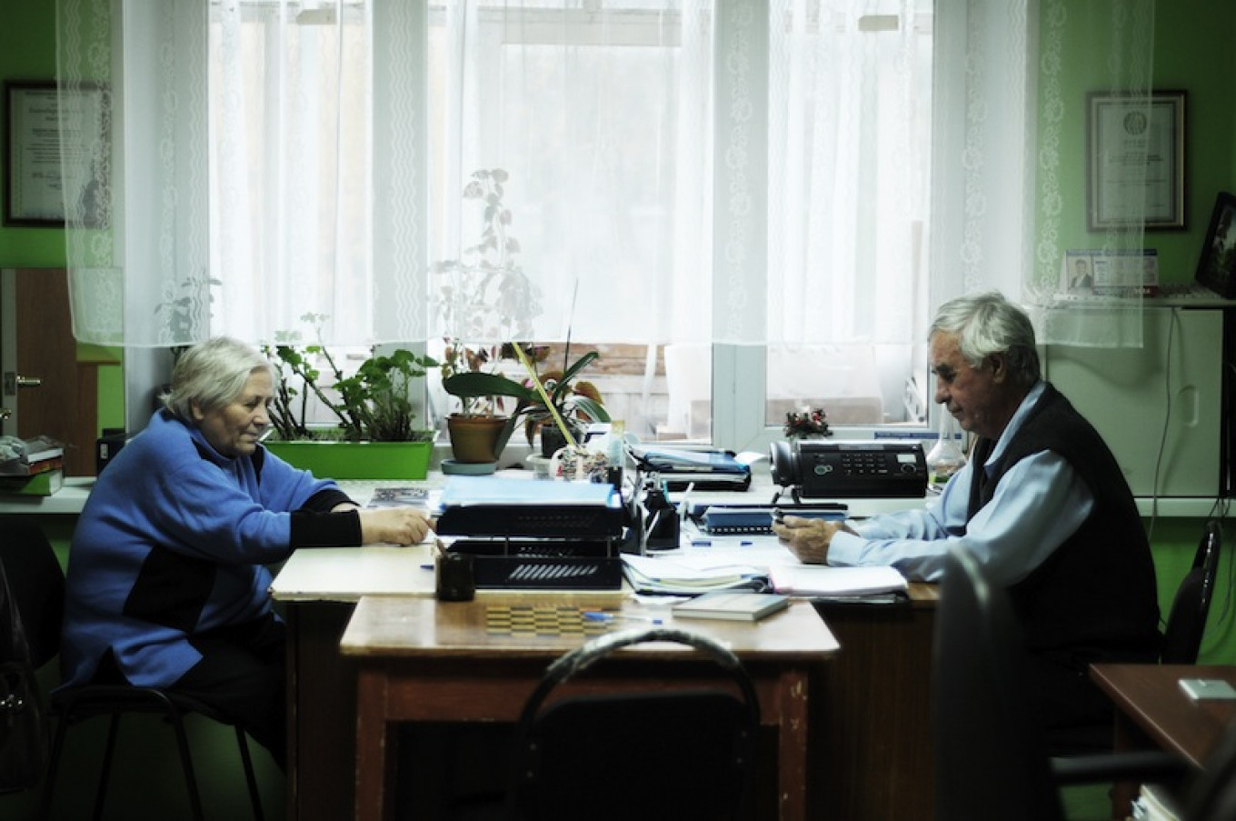 
					Pavel Akimov (R) sitting in the small office of the "Our Memory" group for the descendants of the kulaks forcibly relocated to Surgut in the 1930s. 					 					Eva Hartog				