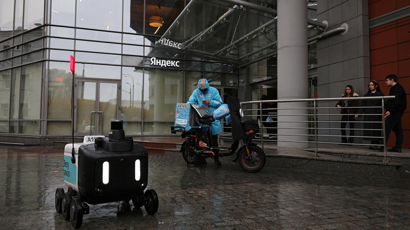 
					A Yandex delivery robot passes a courier outside the Yandex office in Moscow.					 					REUTERS / Anastasia Barashkova				
