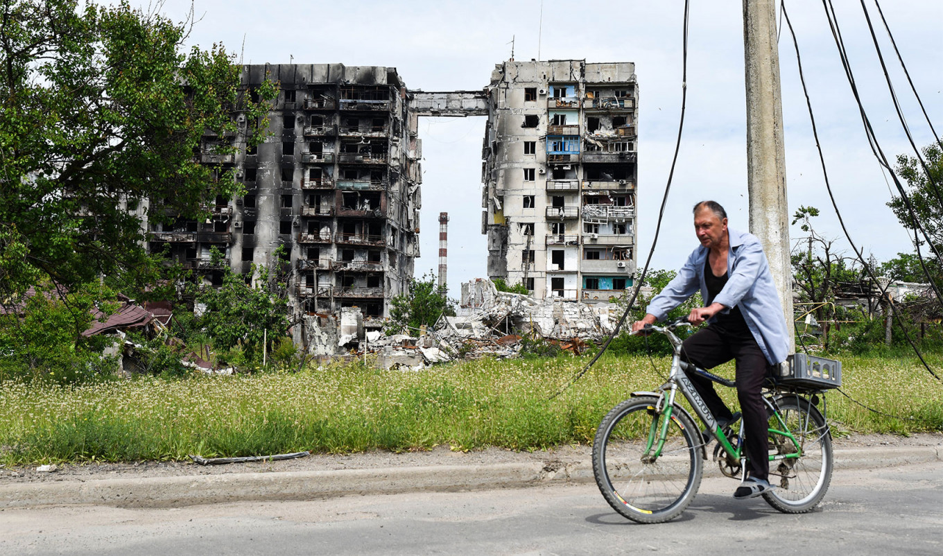 Seorang penduduk setempat mengendarai sepeda di kota Mariupol, Ukraina.  Nikolai Trishin / TASS