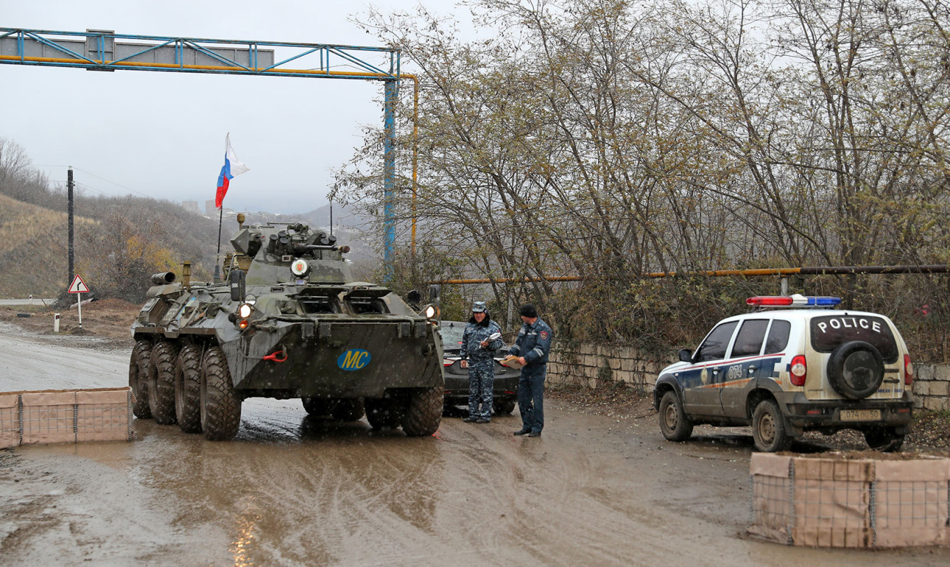 
					
					Material militar de las fuerzas de paz rusas y un coche de policía en un puesto de avanzada en la ciudad de Stepanakert, Nagorno-Karabaj.  Alejandro Ryumin / TASS				