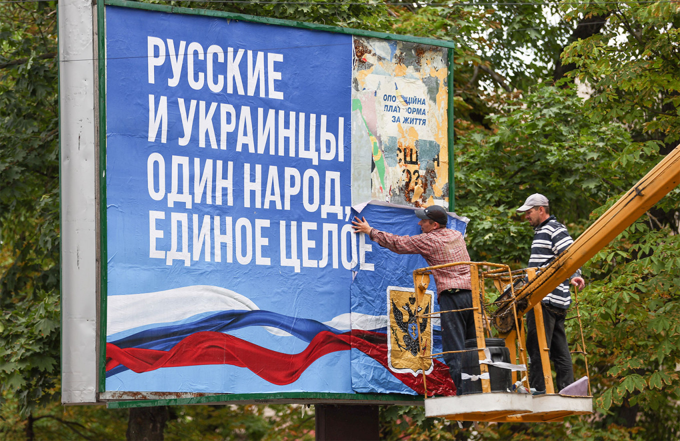 
					Putting up a billboard with a message reading "Russians and Ukrainians are one people" in Kherson.					 					Sergei Bobylev / TASS				