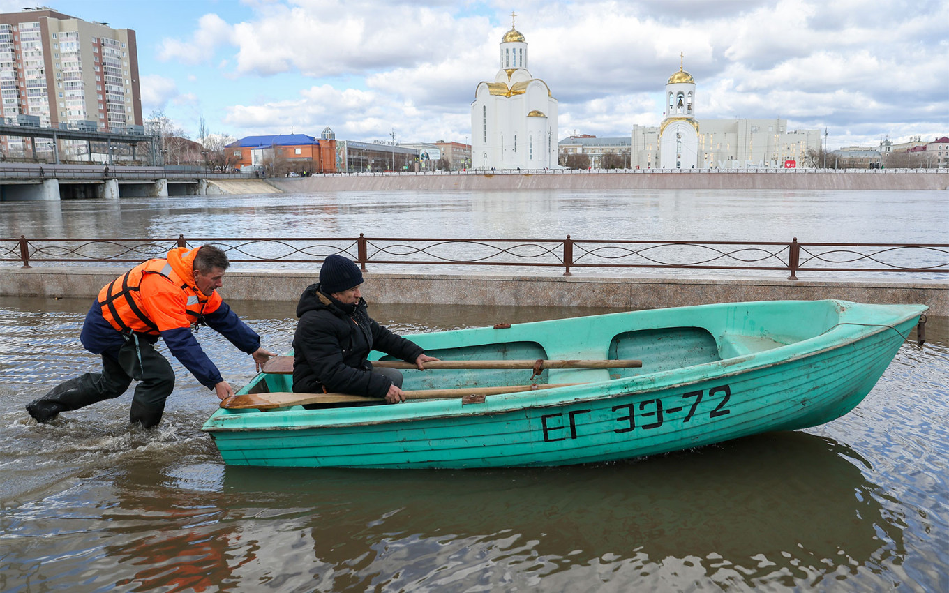 
					A Russian Emergencies Ministry employee pushes a boat near a dam in Kurgan. 					 					Donat Sorokin / TASS				