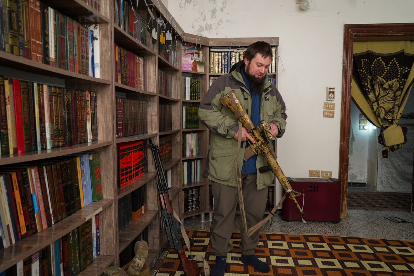 
					In his modest apartment in Idlib, framed by shelves of religious texts, Abu Musa displays a newly acquired firearm.					 					Joseph Roche				