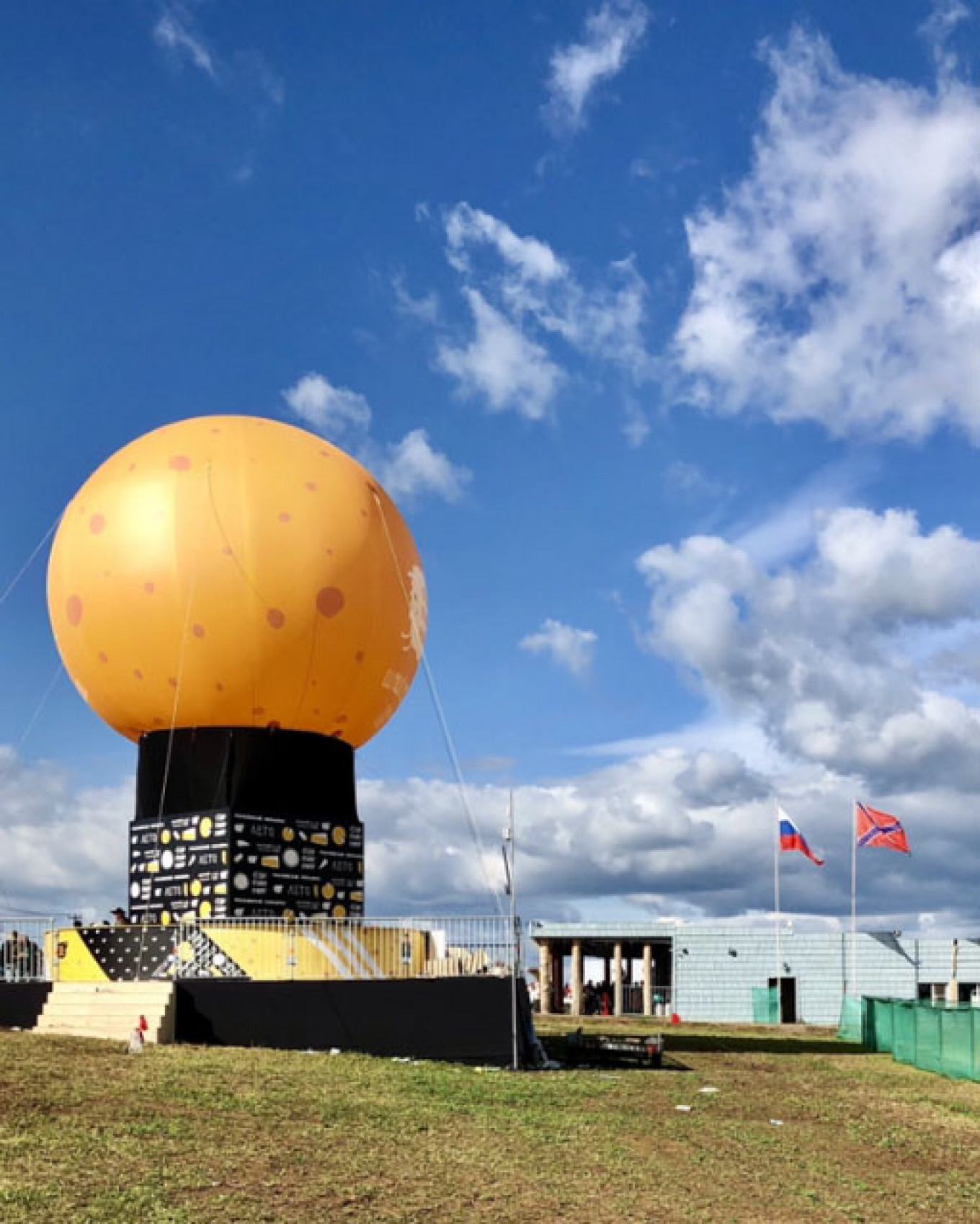 
					The Russian flag and the flag used by Donetsk separatists fly next to an inflatable cheese at the festival.					 					 Emily Ziffer/MT				