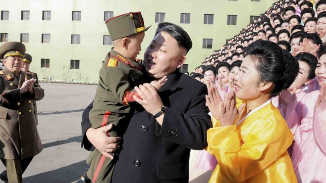 North Korean leader Kim Jong-un holds a boy after a photo session with part...
